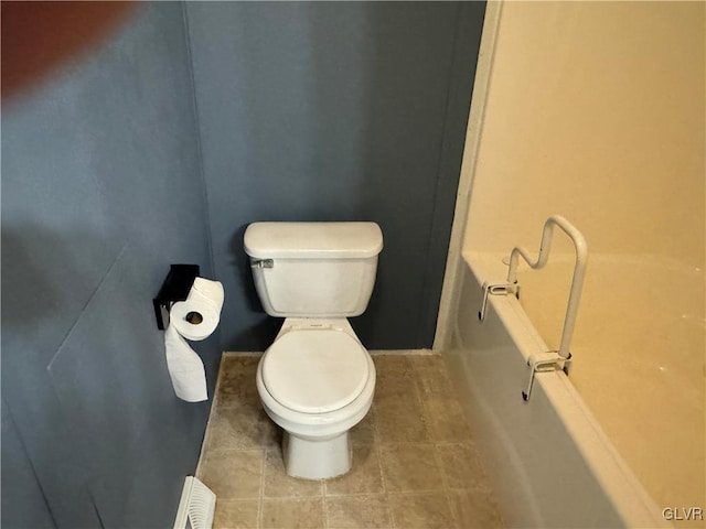 bathroom featuring a washtub, tile patterned flooring, and toilet