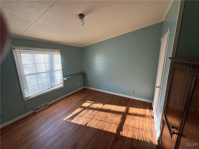 empty room featuring a textured ceiling and dark hardwood / wood-style flooring