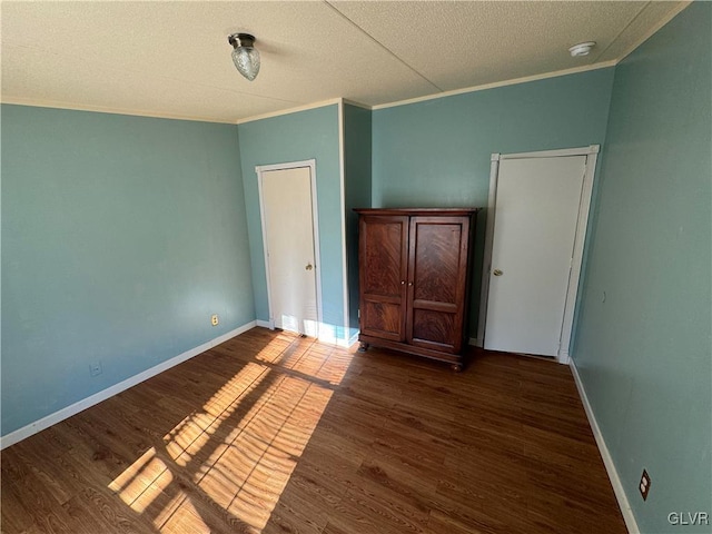 unfurnished bedroom with dark hardwood / wood-style flooring, a textured ceiling, and ornamental molding