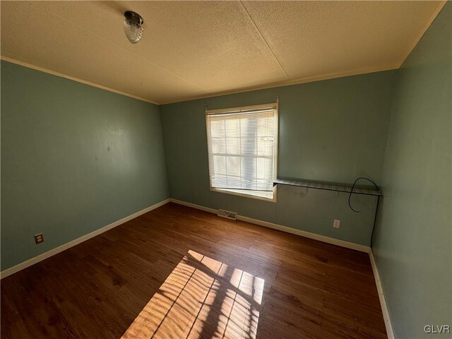 spare room with dark hardwood / wood-style flooring, a textured ceiling, and ornamental molding