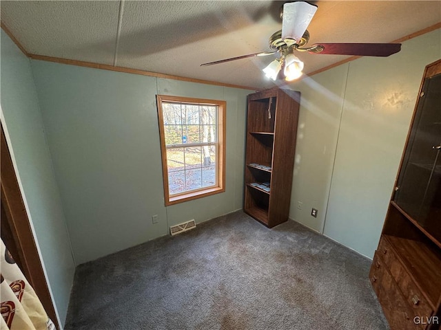 unfurnished bedroom with ceiling fan, crown molding, a textured ceiling, and dark colored carpet