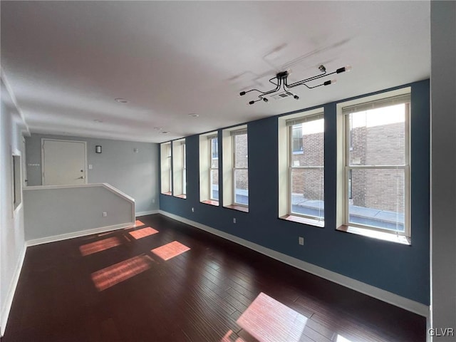 spare room featuring dark hardwood / wood-style flooring and a healthy amount of sunlight