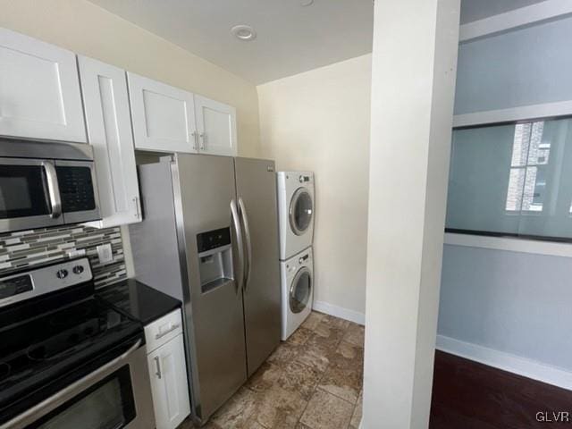 kitchen featuring backsplash, stacked washing maching and dryer, white cabinets, and stainless steel appliances