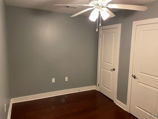 empty room featuring ceiling fan and dark hardwood / wood-style flooring