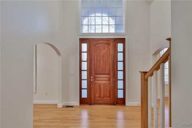 foyer entrance with light wood-type flooring and a towering ceiling