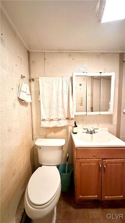 bathroom featuring vanity, tile walls, and toilet