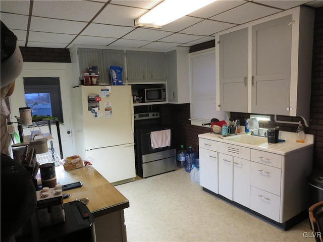 kitchen featuring appliances with stainless steel finishes, a paneled ceiling, gray cabinets, and sink