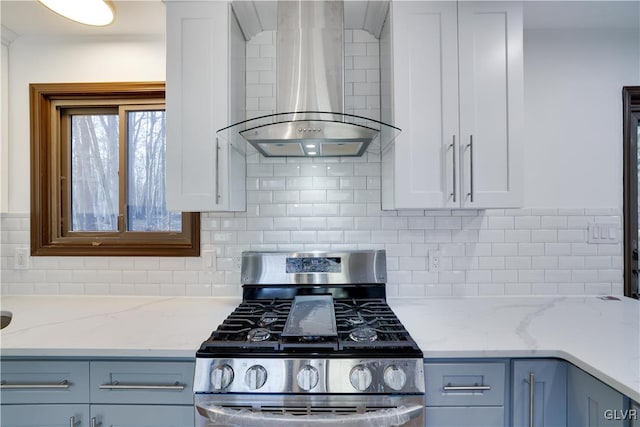 kitchen featuring stainless steel range with gas stovetop, white cabinetry, light stone counters, and wall chimney range hood