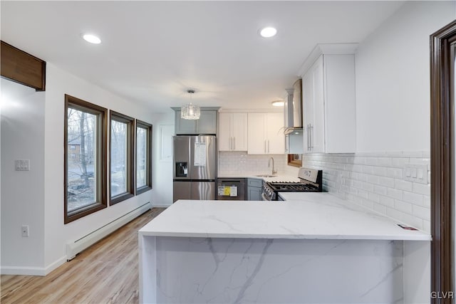 kitchen with pendant lighting, white cabinets, baseboard heating, appliances with stainless steel finishes, and kitchen peninsula