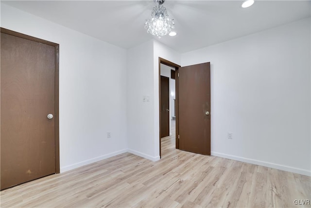 unfurnished bedroom with a chandelier, light hardwood / wood-style floors, and a closet