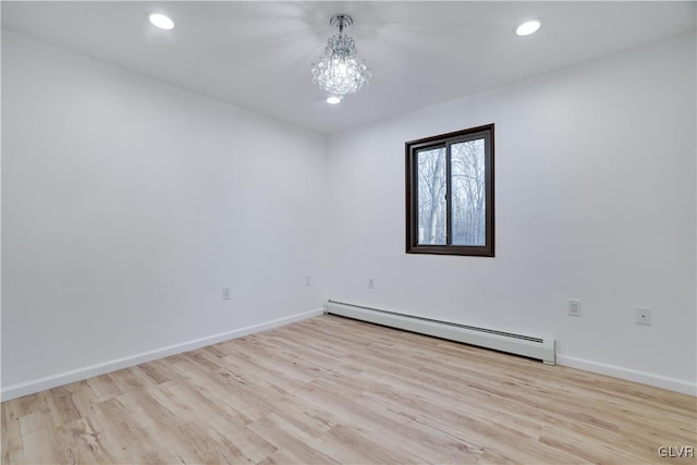 empty room featuring an inviting chandelier, a baseboard radiator, and light hardwood / wood-style floors