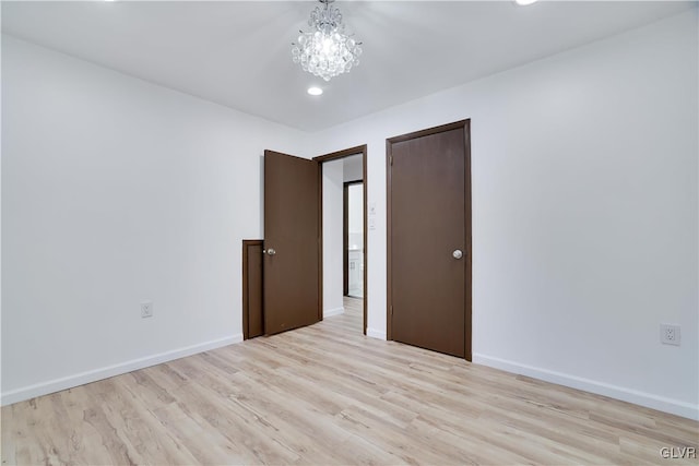 unfurnished room with a chandelier and light hardwood / wood-style flooring