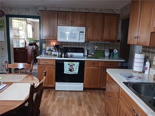 kitchen with light wood-type flooring, decorative backsplash, white appliances, and sink