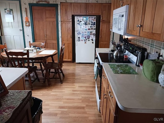 kitchen with decorative backsplash, white appliances, and light hardwood / wood-style floors