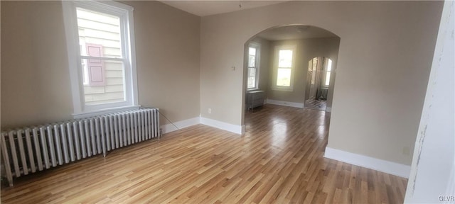 spare room with radiator heating unit and light hardwood / wood-style flooring