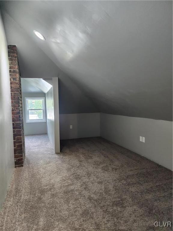 additional living space with carpet flooring and lofted ceiling