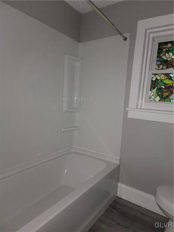 bathroom featuring wood-type flooring, toilet, and shower / washtub combination