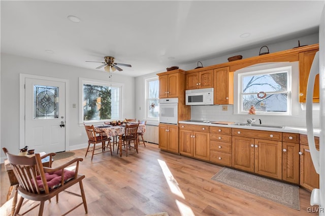 kitchen with plenty of natural light, white appliances, sink, and light hardwood / wood-style flooring