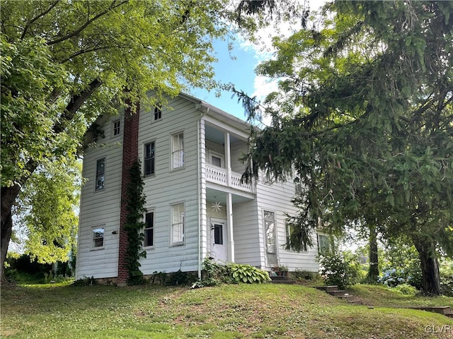 view of front facade with a balcony and a front lawn