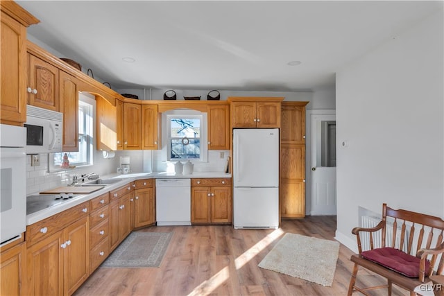 kitchen with decorative backsplash, sink, white appliances, and light wood-type flooring