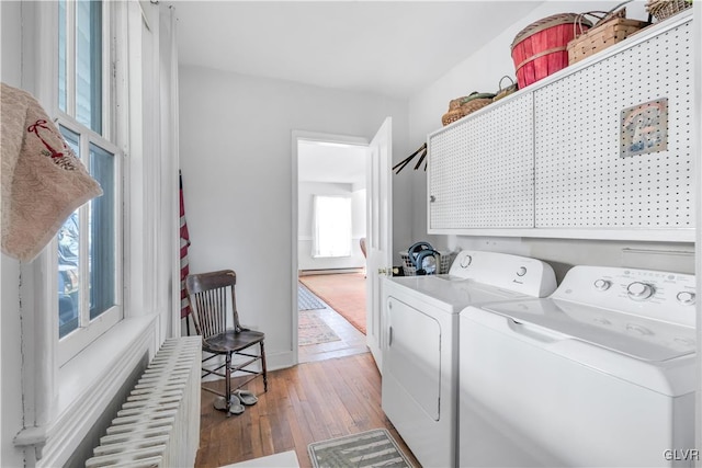 washroom with cabinets, wood-type flooring, radiator heating unit, and washer and dryer