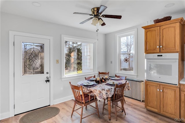 dining room with radiator, ceiling fan, and light hardwood / wood-style floors