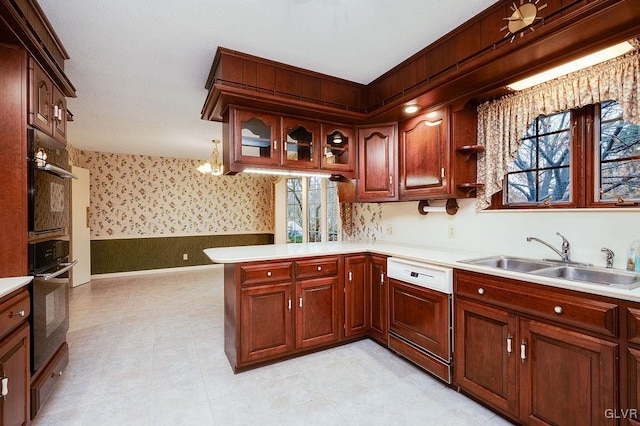 kitchen featuring paneled dishwasher, kitchen peninsula, sink, decorative light fixtures, and a chandelier