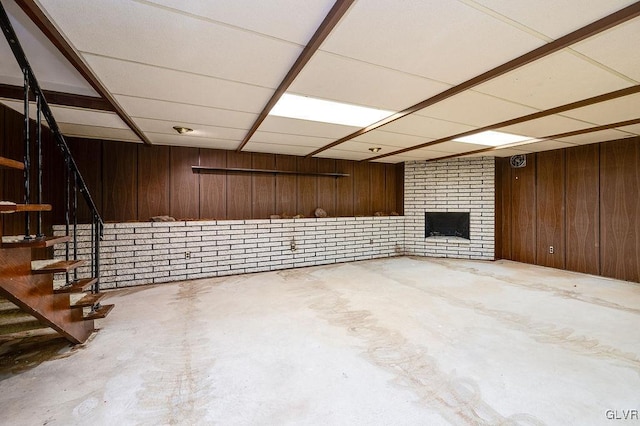 basement featuring a brick fireplace and wooden walls