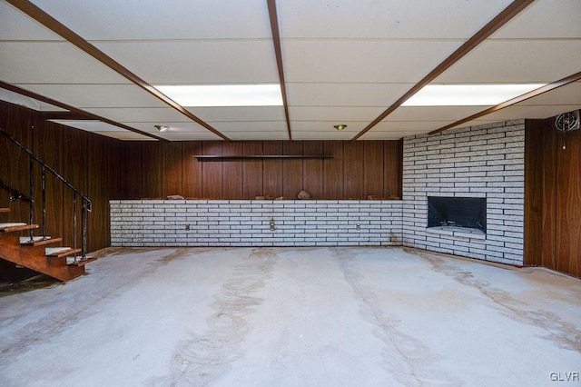 basement with a brick fireplace and wooden walls