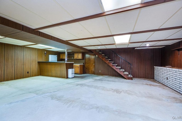 basement with white refrigerator and wooden walls