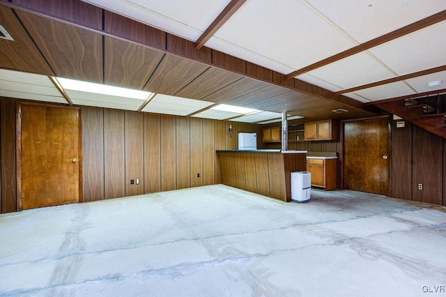 basement featuring white fridge and wood walls