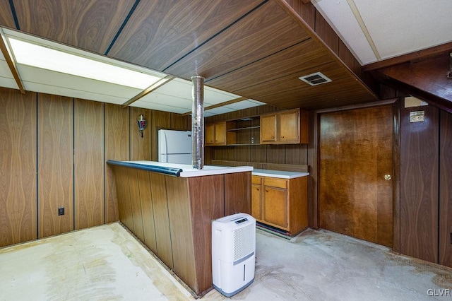 kitchen featuring kitchen peninsula, wood walls, and white refrigerator