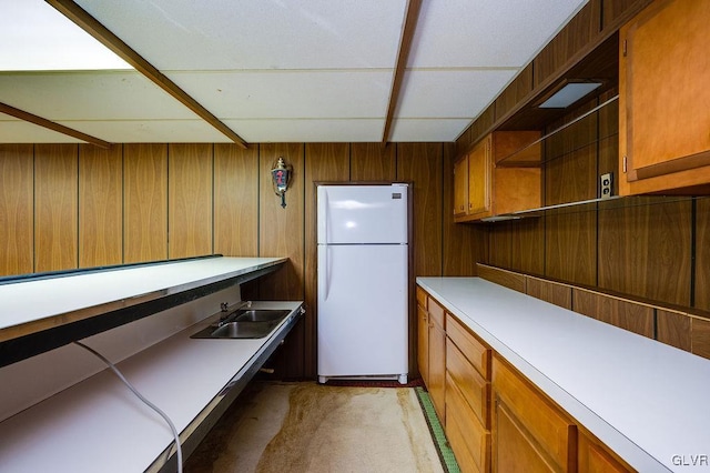 kitchen with wood walls, white fridge, and sink