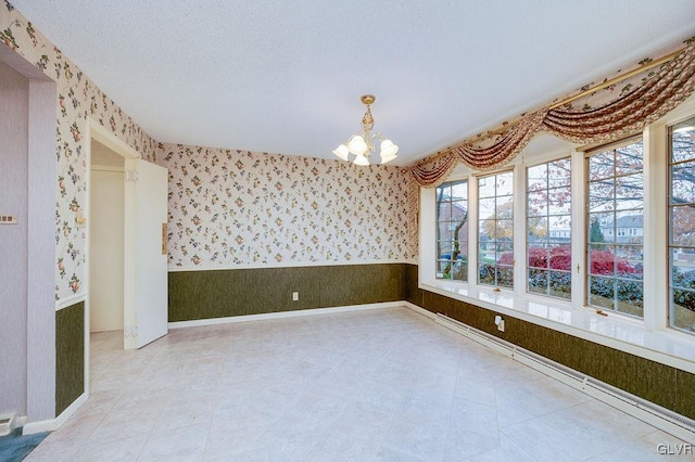 empty room with a chandelier and a textured ceiling