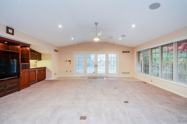 unfurnished living room with light carpet, french doors, ceiling fan, and vaulted ceiling