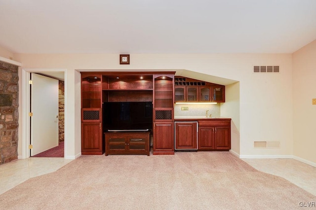 unfurnished living room featuring light colored carpet and indoor wet bar