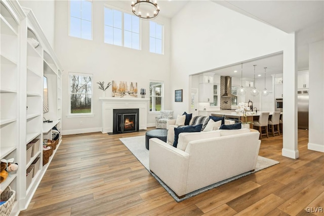 living room featuring a high ceiling, light hardwood / wood-style floors, a notable chandelier, and sink