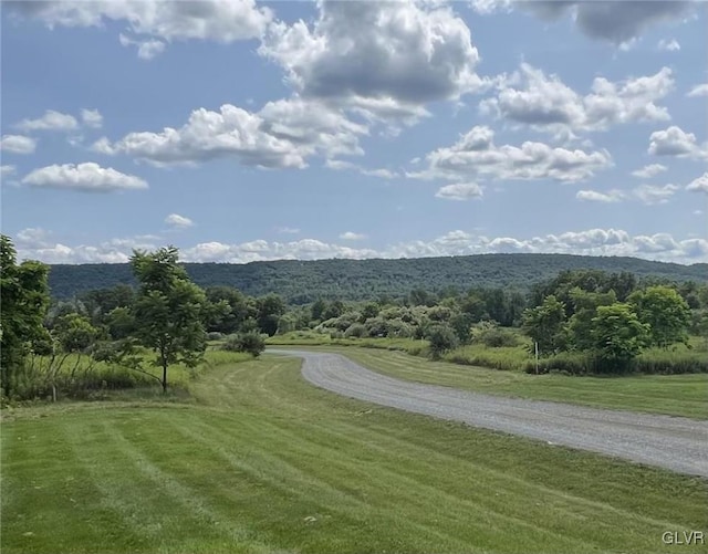 surrounding community with a mountain view and a lawn