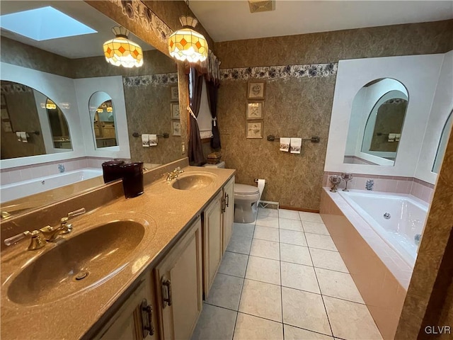 bathroom featuring a skylight, vanity, a relaxing tiled tub, tile patterned flooring, and toilet