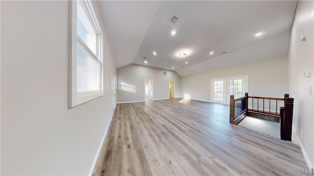 living room with french doors, vaulted ceiling, and light wood-type flooring