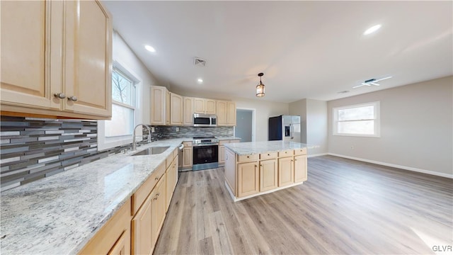 kitchen with decorative backsplash, stainless steel appliances, sink, a center island, and light hardwood / wood-style floors