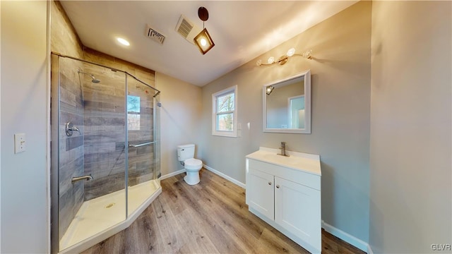 bathroom featuring wood-type flooring, vanity, toilet, and a shower with door