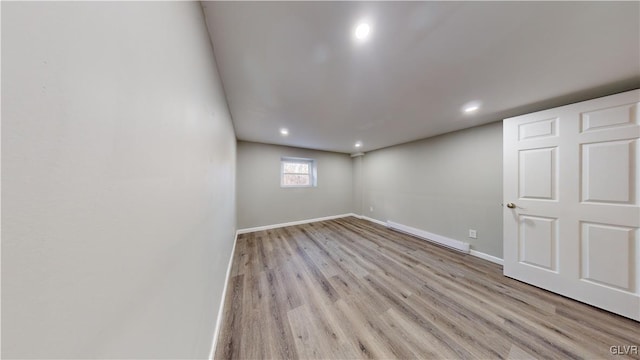 basement featuring light hardwood / wood-style floors and a baseboard heating unit