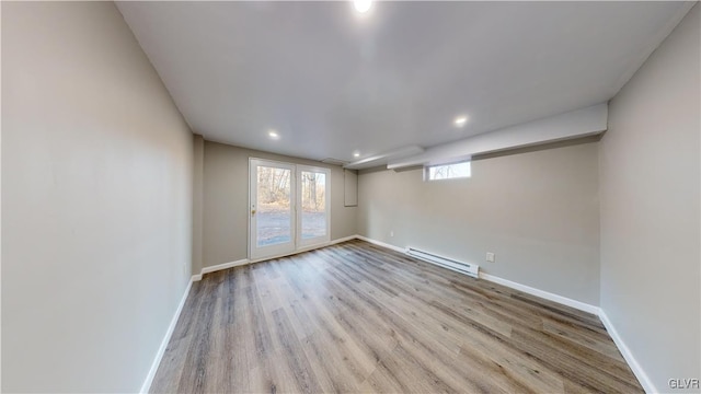 spare room featuring baseboard heating and light hardwood / wood-style flooring