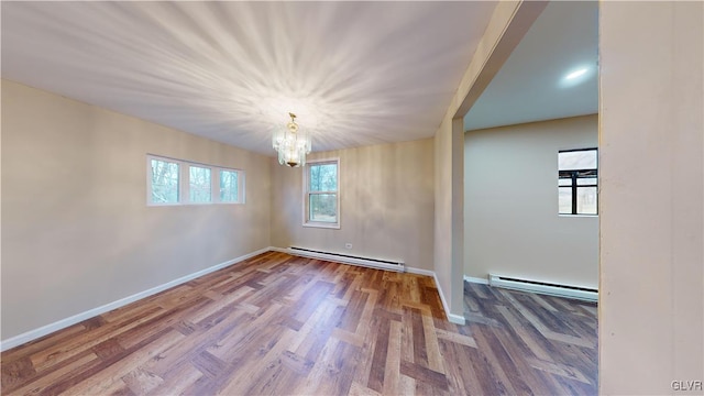 spare room with a baseboard radiator, hardwood / wood-style flooring, and a notable chandelier