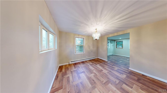 unfurnished room with wood-type flooring, a chandelier, and a baseboard heating unit