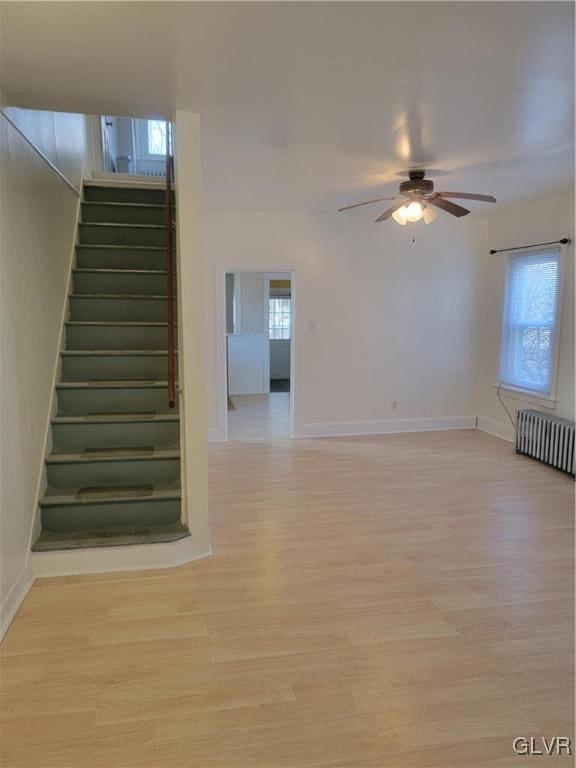 stairway featuring hardwood / wood-style floors, ceiling fan, and radiator heating unit