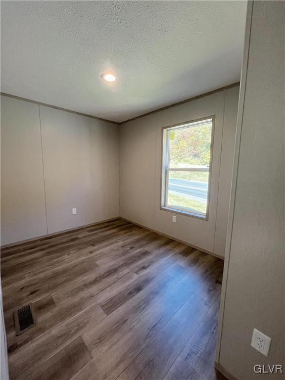 spare room featuring hardwood / wood-style floors and a textured ceiling