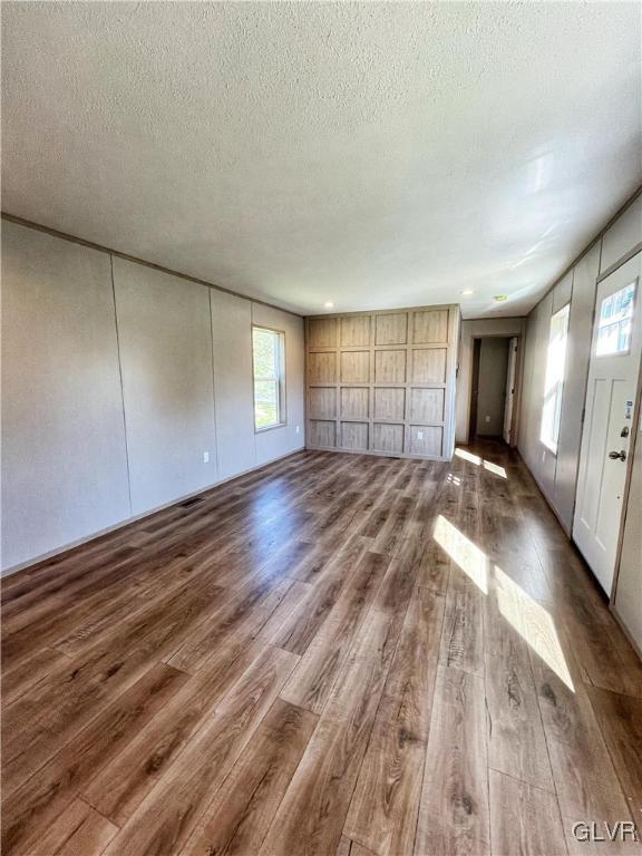 unfurnished living room with plenty of natural light, dark hardwood / wood-style flooring, and a textured ceiling