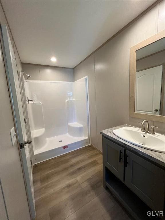 bathroom with hardwood / wood-style floors, vanity, and walk in shower
